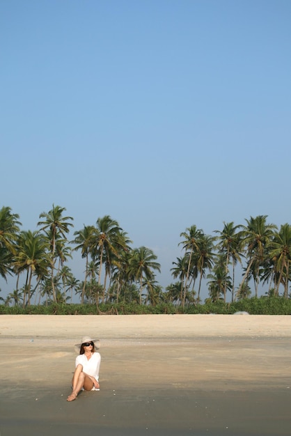 Photo femme au chapeau blanc allongé sur la plage dans un pays tropical