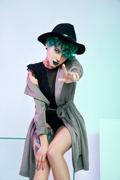 Femme au chapeau avec coloration verte créative cheveux et maquillage, mèches de cheveux toxiques.