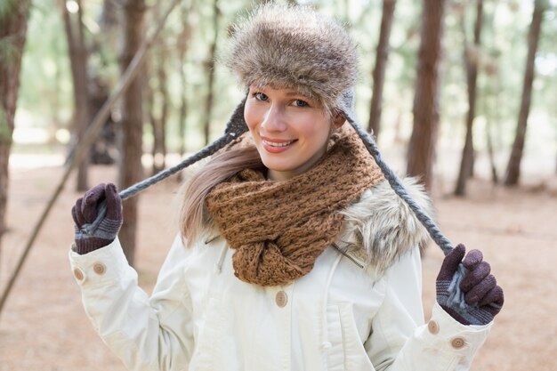 Femme au chapeau de fourrure avec écharpe en laine et veste dans les bois