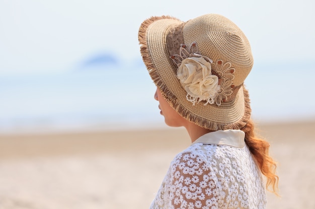 Femme au chapeau de luxe regardant la mer