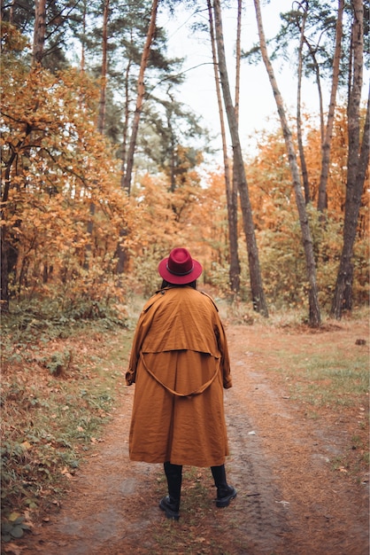 Femme au chapeau et manteau dans les bois