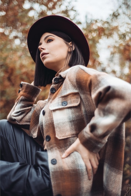 Femme au chapeau et manteau dans les bois