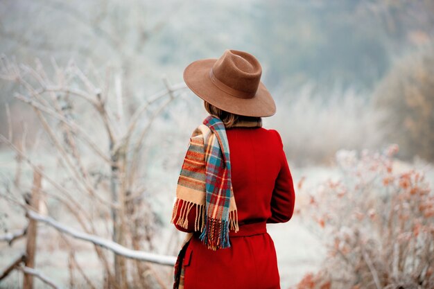 Femme au chapeau et manteau rouge dans la campagne d'hiver