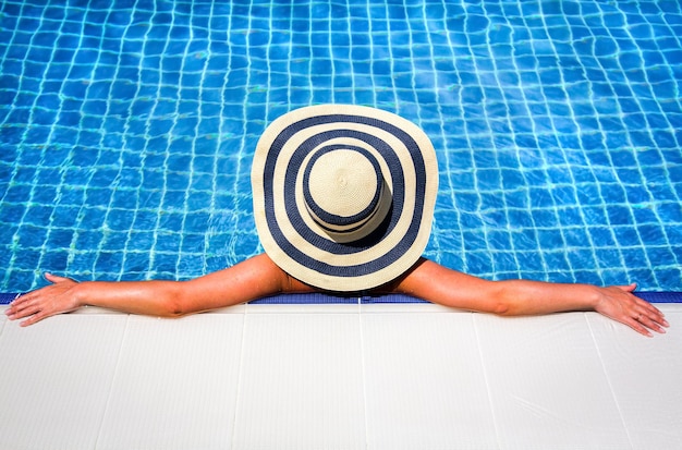 Femme au chapeau de paille piscine relaxante. Composition du bas espace de copie parfait pour vos annonces textuelles.
