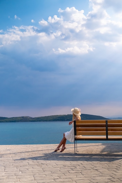 Femme au chapeau de paille soleil assis sur un banc en bois à Hermione Marina Grèce