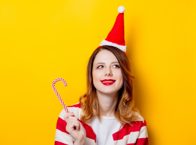 Femme au chapeau de père Noël avec une canne en bonbon