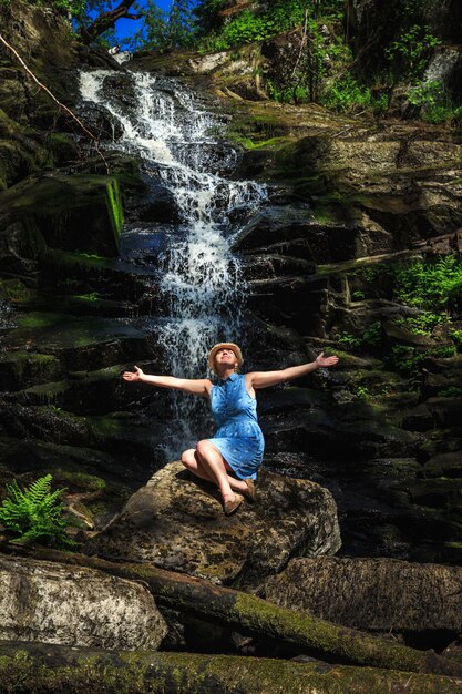 Femme au chapeau, profitant de la nature près de la cascade de la forêt.