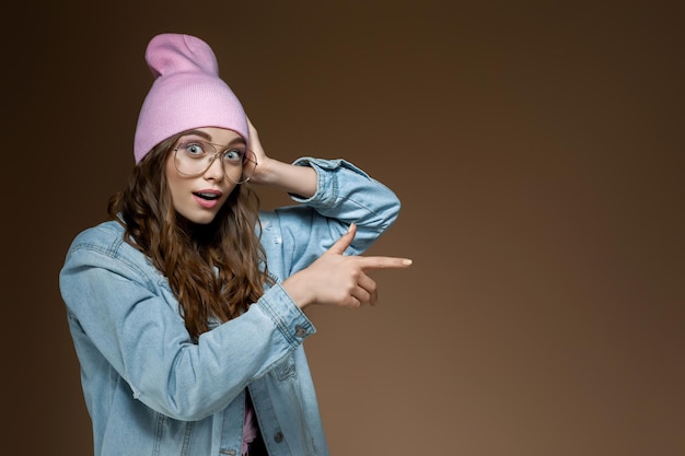 La femme au chapeau rose pointe avec sa main