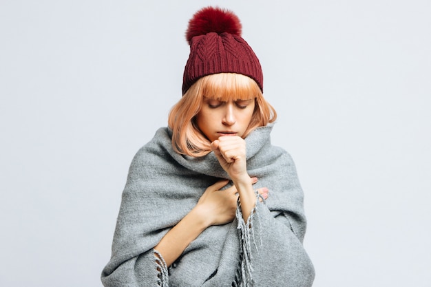 Femme au chapeau rouge, enveloppée dans une écharpe chaude toussant