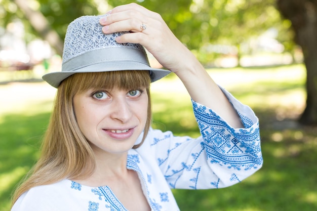 Une femme au chapeau tient son chapeau.