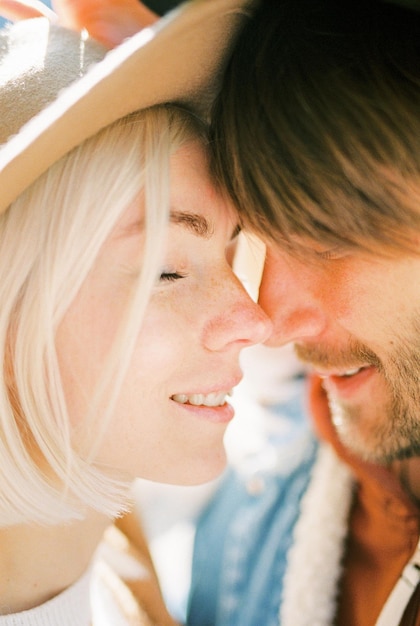 Femme au chapeau touche le nez d'un homme avec son nez Portrait