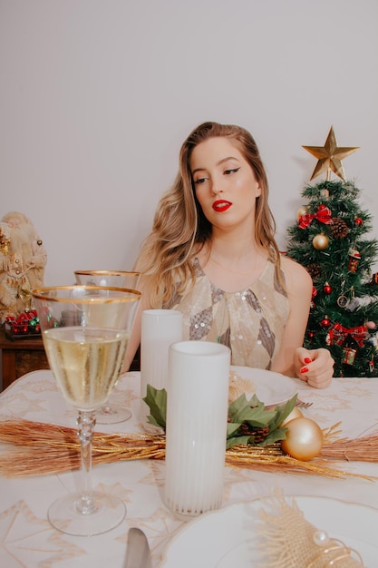 Femme au dîner de Noël avec du vin mousseux et des cadeaux