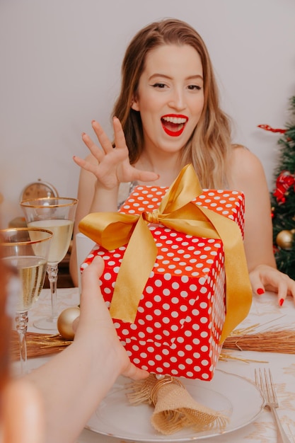 Femme au dîner de Noël avec du vin mousseux et des cadeaux