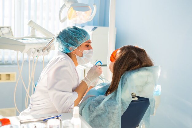 Femme au fauteuil du dentiste lors d'une intervention dentaire.