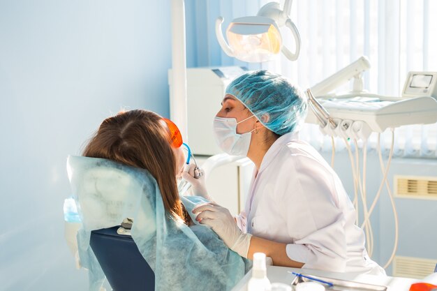 Femme au fauteuil du dentiste lors d'une intervention dentaire.