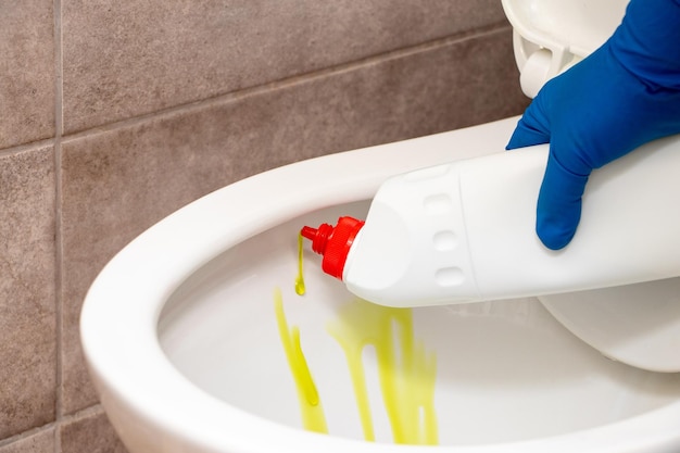 Une femme au foyer applique du gel nettoyant sur les toilettes