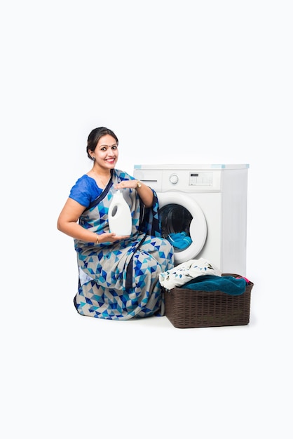 Femme au foyer asiatique indienne souriante à Saree debout près de la machine à laver avec panier de vêtements