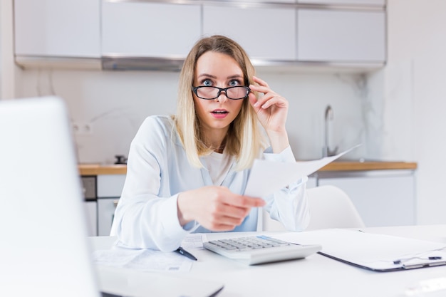 femme au foyer assis une table dans la cuisine de la maison un accord incompréhensible avec les factures et les prêts de la paperasse