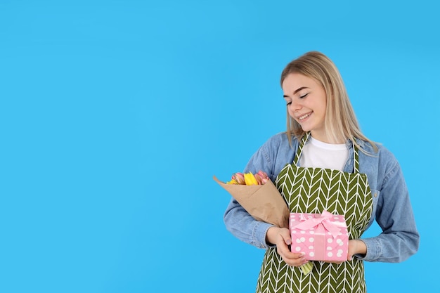 Femme au foyer avec bouquet et coffret cadeau sur fond bleu