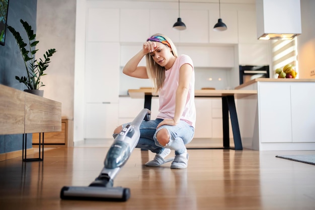 Une femme au foyer fatiguée accroupie et faisant une pause dans le nettoyage de la maison