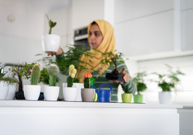 femme au foyer à la maison arrosage des plantes dans la cuisine