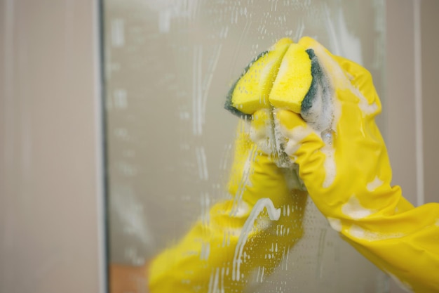 Femme au foyer nettoyant le miroir dans la salle de bain