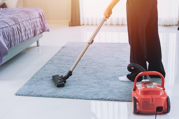 Femme au foyer nettoyant la poussière de la maison Passez l'aspirateur sur le tapis dans la chambre le matin en utilisant la technologie propre concept d'entretien ménager