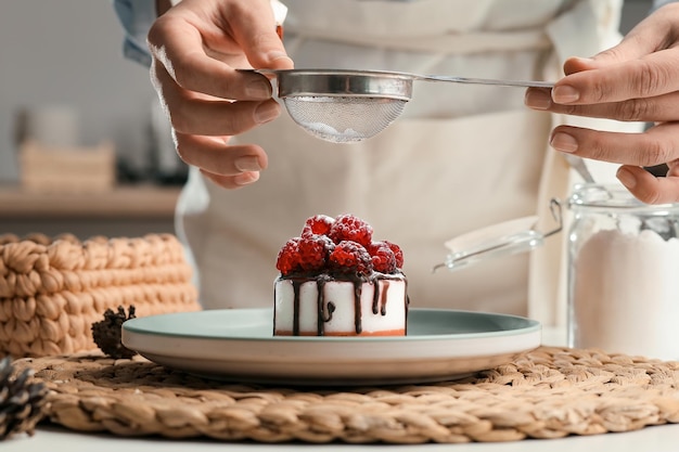 La femme au foyer prépare un petit gâteau saupoudré de sucre