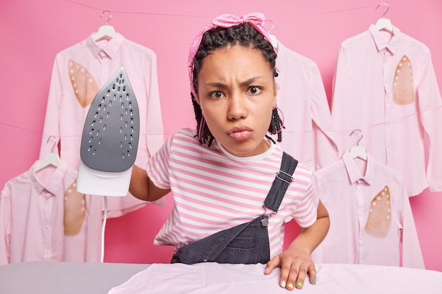 La femme au foyer repasse les vêtements de famille.