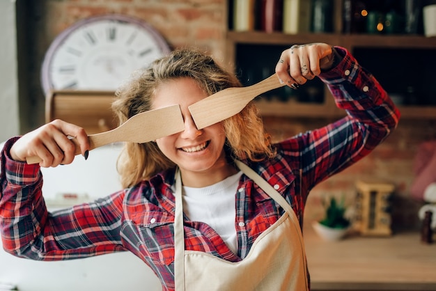 Femme au foyer se couvre les yeux avec des spatules en bois