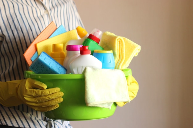 La femme au foyer tient un panier avec des produits de nettoyage et de désinfection