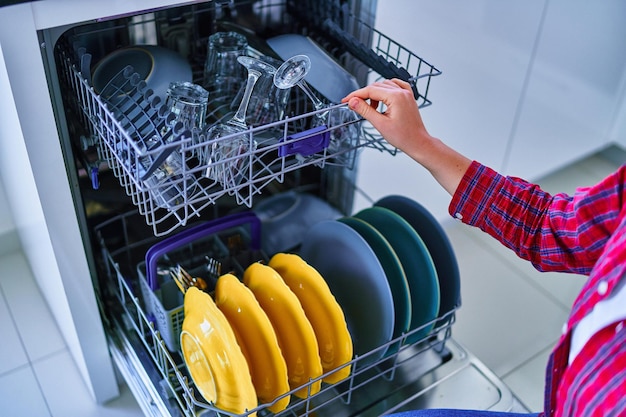 Femme au foyer utilisant un lave-vaisselle moderne pour laver la vaisselle dans la cuisine à domicile