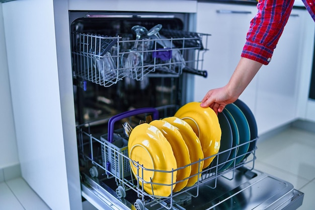 Femme au foyer utilisant un lave-vaisselle moderne pour laver la vaisselle dans la cuisine à domicile