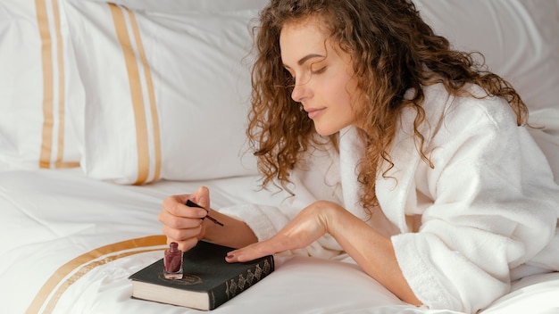 Photo femme au lit, appliquer du vernis à ongles