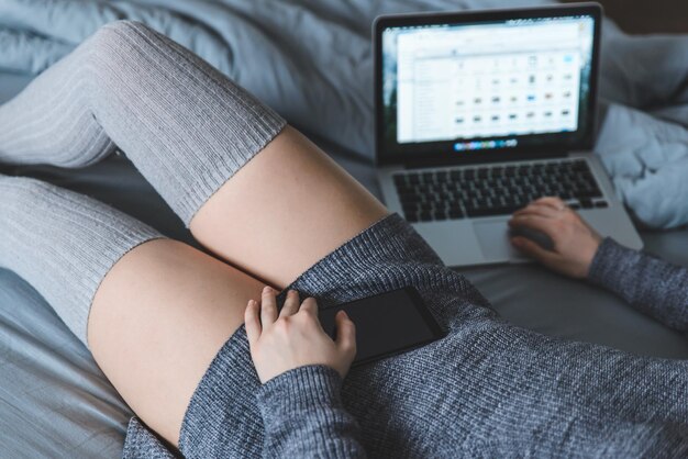 Femme au lit avec ordinateur portable et smartphone en mains. concept de mode de vie