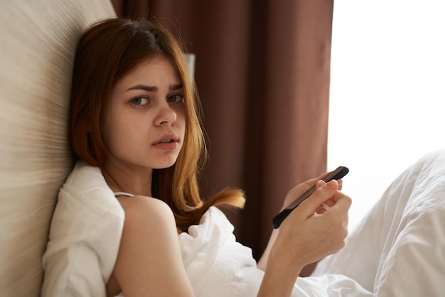 Femme au lit sous les couvertures près de la vue recadrée de la fenêtre