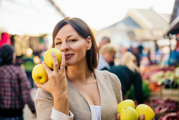 Femme au marché aux fruits avec des pommes dans les mains.