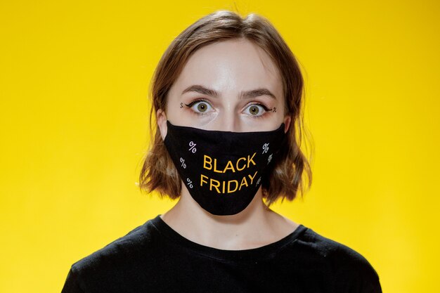 Femme au masque facial avec des sacs à provisions du vendredi noir dans la vente des mains pendant la pandémie