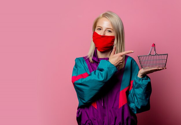 Femme au masque facial et vêtements des années 80 avec panier sur rose