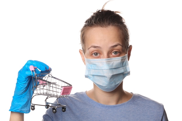 Femme au masque médiatique et gants tient un chariot isolé sur blanc