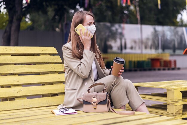 Femme au masque médical parlant au téléphone