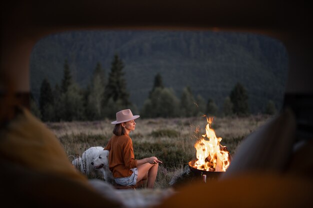 Femme au pique-nique avec feu de joie dans les montagnes