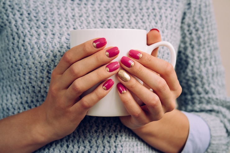 Photo femme au pull gris tenant dans ses mains avec un vernis à ongles brillant grande tasse blanche