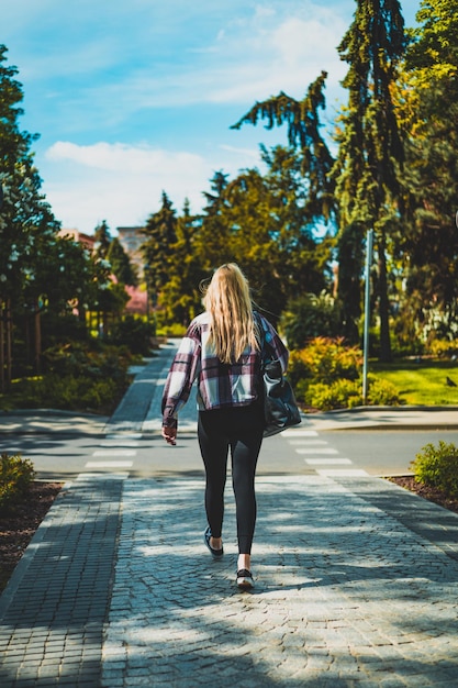 Femme au soleil sur le chemin du parc de la ville