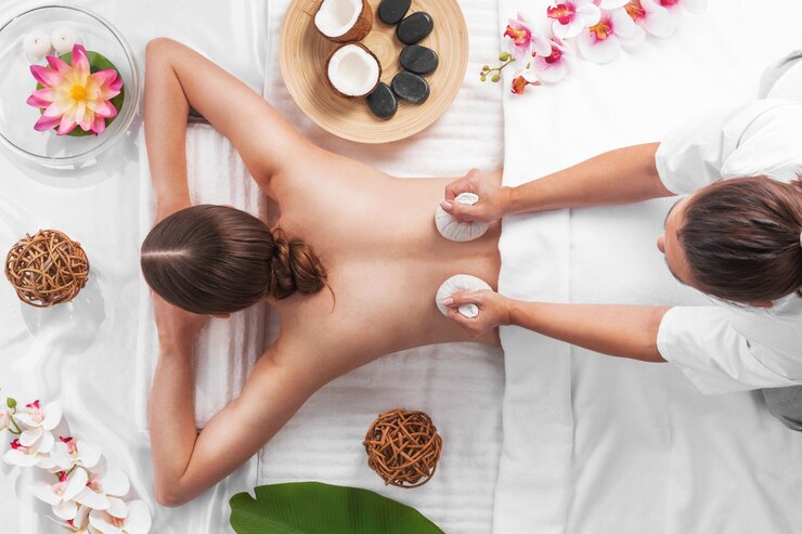 Photo femme au spa thai massage remorquage vue, concept de soins de beauté. orchidées et fleurs de lotus pierres de noix de coco et sachets d'herbes