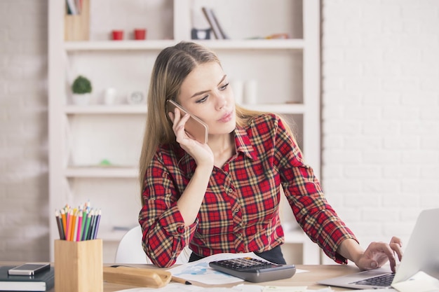 Femme au téléphone à l'aide d'un ordinateur portable