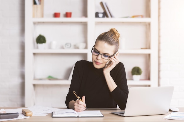 Femme au téléphone faisant de la paperasse