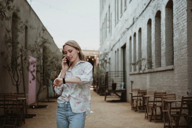 Photo femme au téléphone marchant dans la rue en regardant l'heure