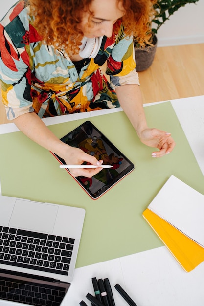 Femme au visage sérieux s'appuyant sur une tablette graphique regardant le grand écran