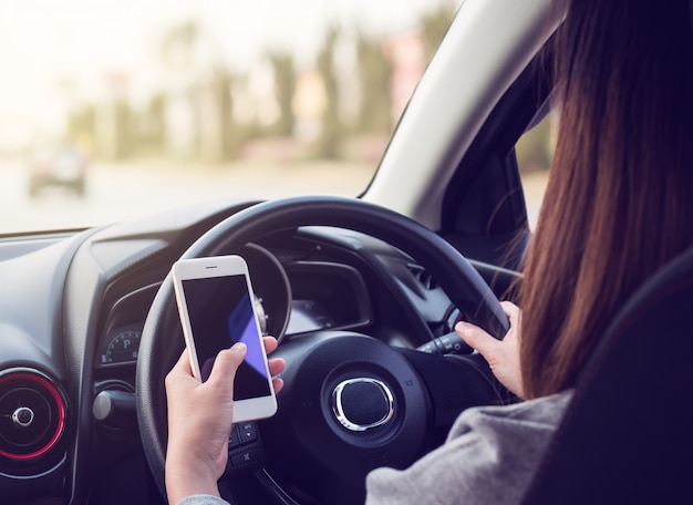 Femme au volant et à l&#39;aide de smartphone sur route